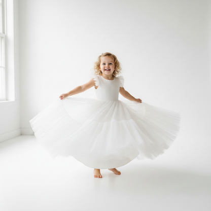 Toddler girl in white ruffle sleeve ball gown twirling in studio